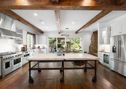 a spacious, modern-rustic kitchen featuring a large central island with a concrete top and an industrial metal base