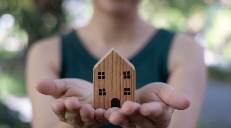Woman holding a wooden house in woods to support Eco-conscious millennials