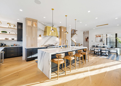 a modern kitchen with a large marble-topped island and wooden counter stools
