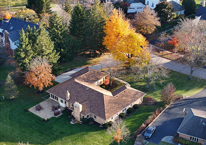 an aerial view of a single-story ranch-style residential home surrounded by trees