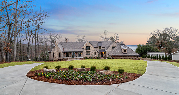 a large, luxury transitional or European-style stone house nestled in a spacious, scenic landscape